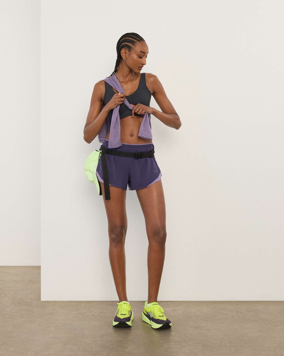 A woman wearing New Balance standing in front a white wall.