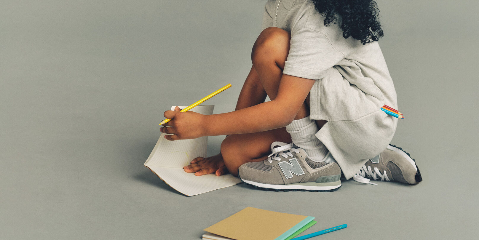 Child sitting on the ground wearing New Balance