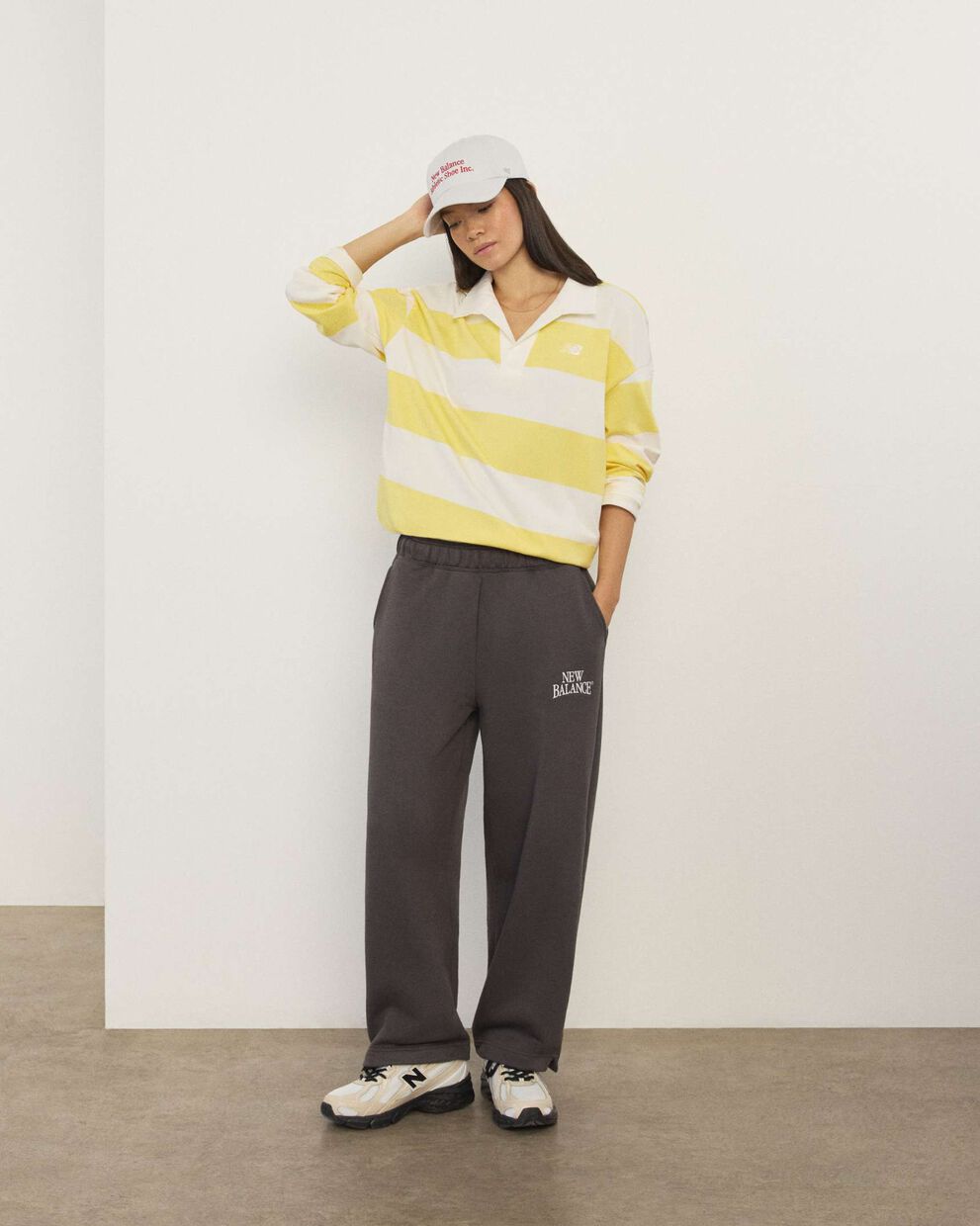 A woman wearing New Balance standing in front a white wall.