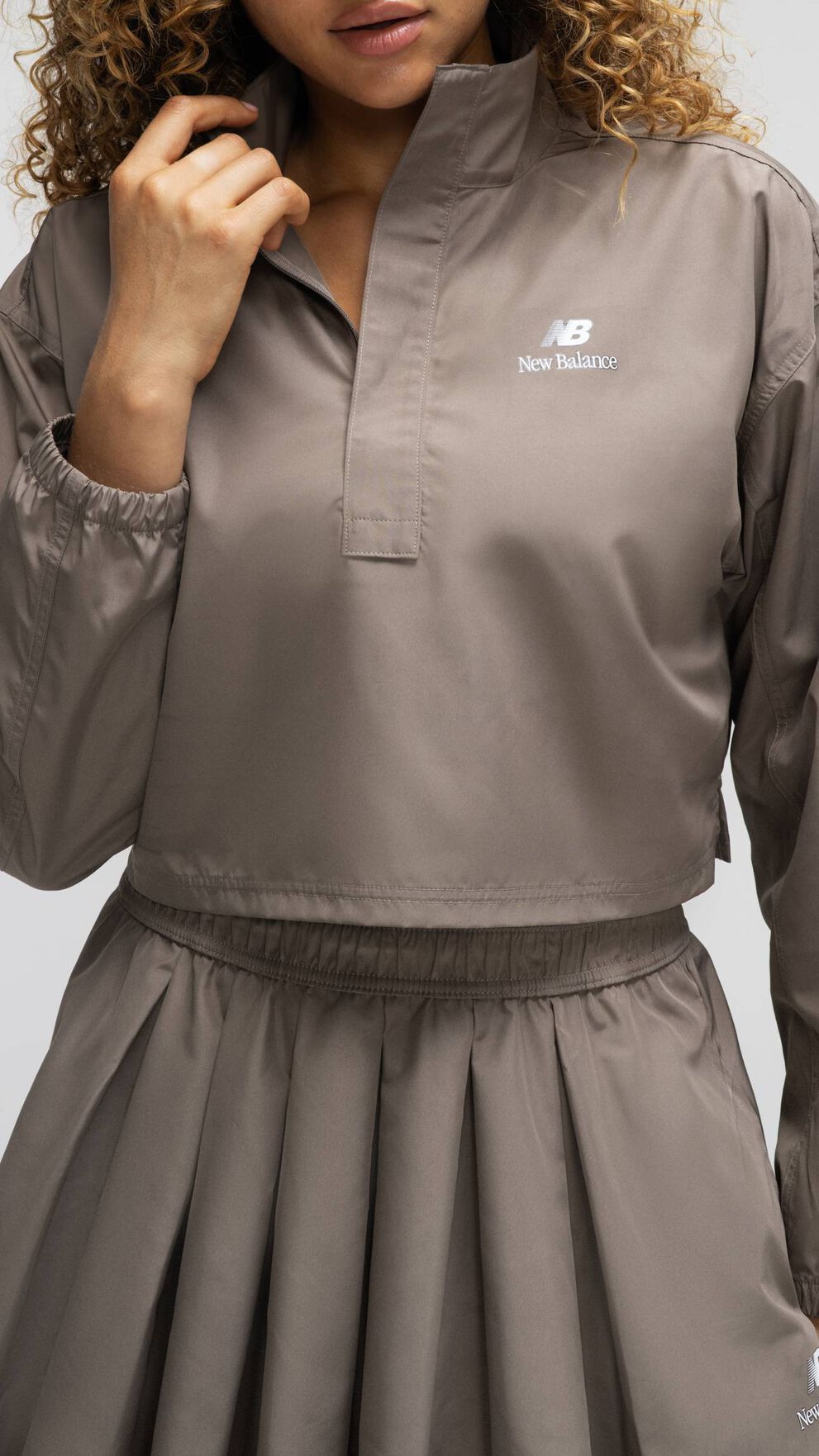 A woman wearing New Balance standing against a grey studio backdrop 