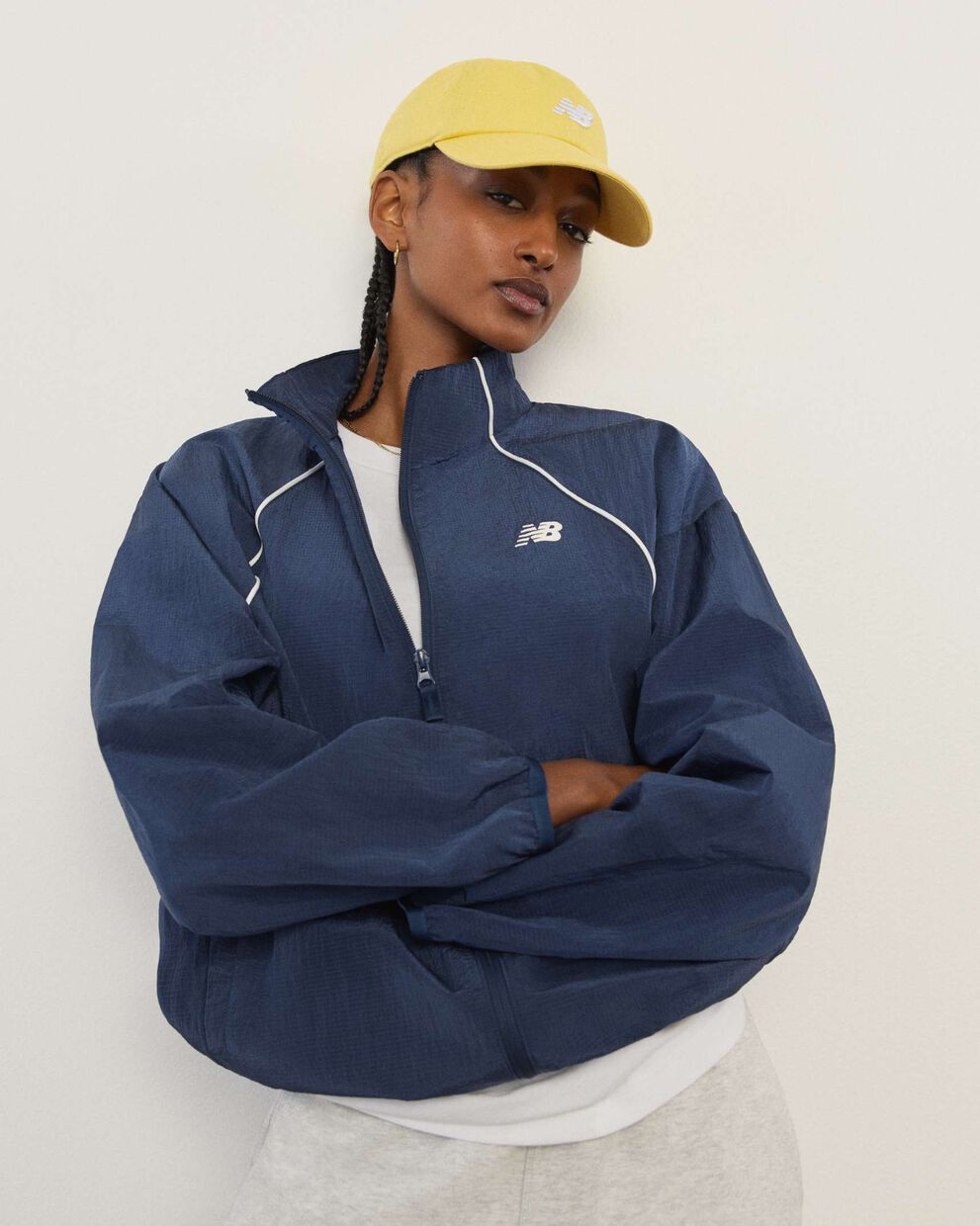 A woman wearing New Balance standing in front a white wall.