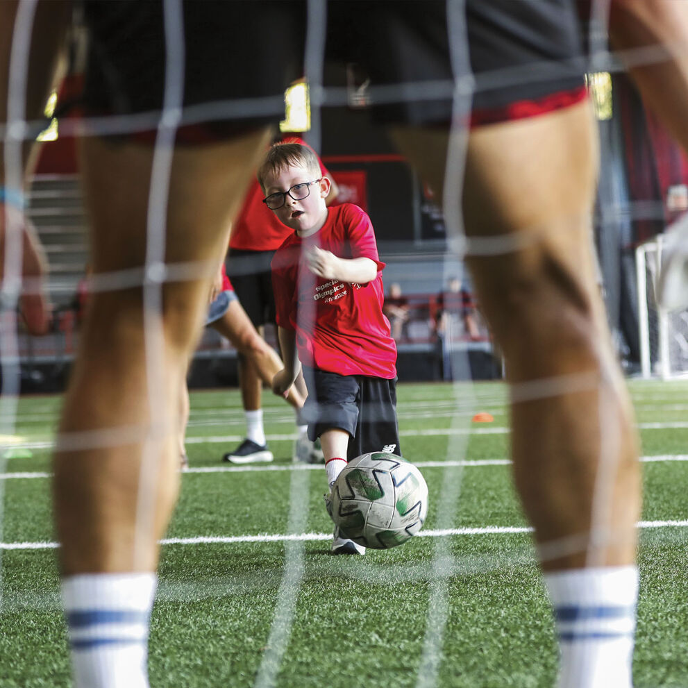 Several light-skinned children practicing soccer skills on a field.